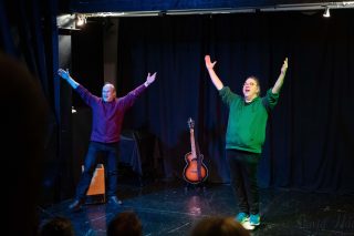 Kuvassa näyttelijät kädet ylhäällä.